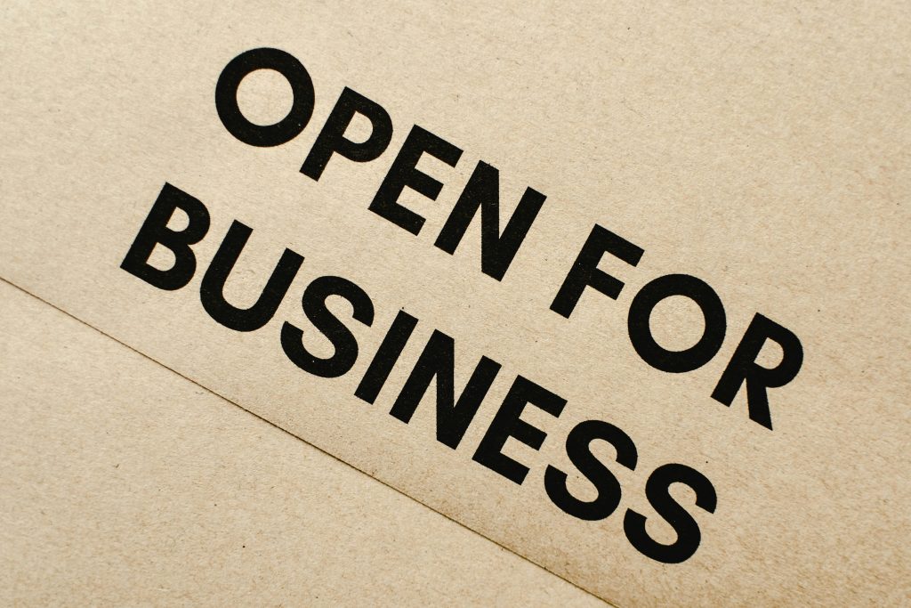 Close-up of an 'Open for Business' sign on a textured brown paper background.